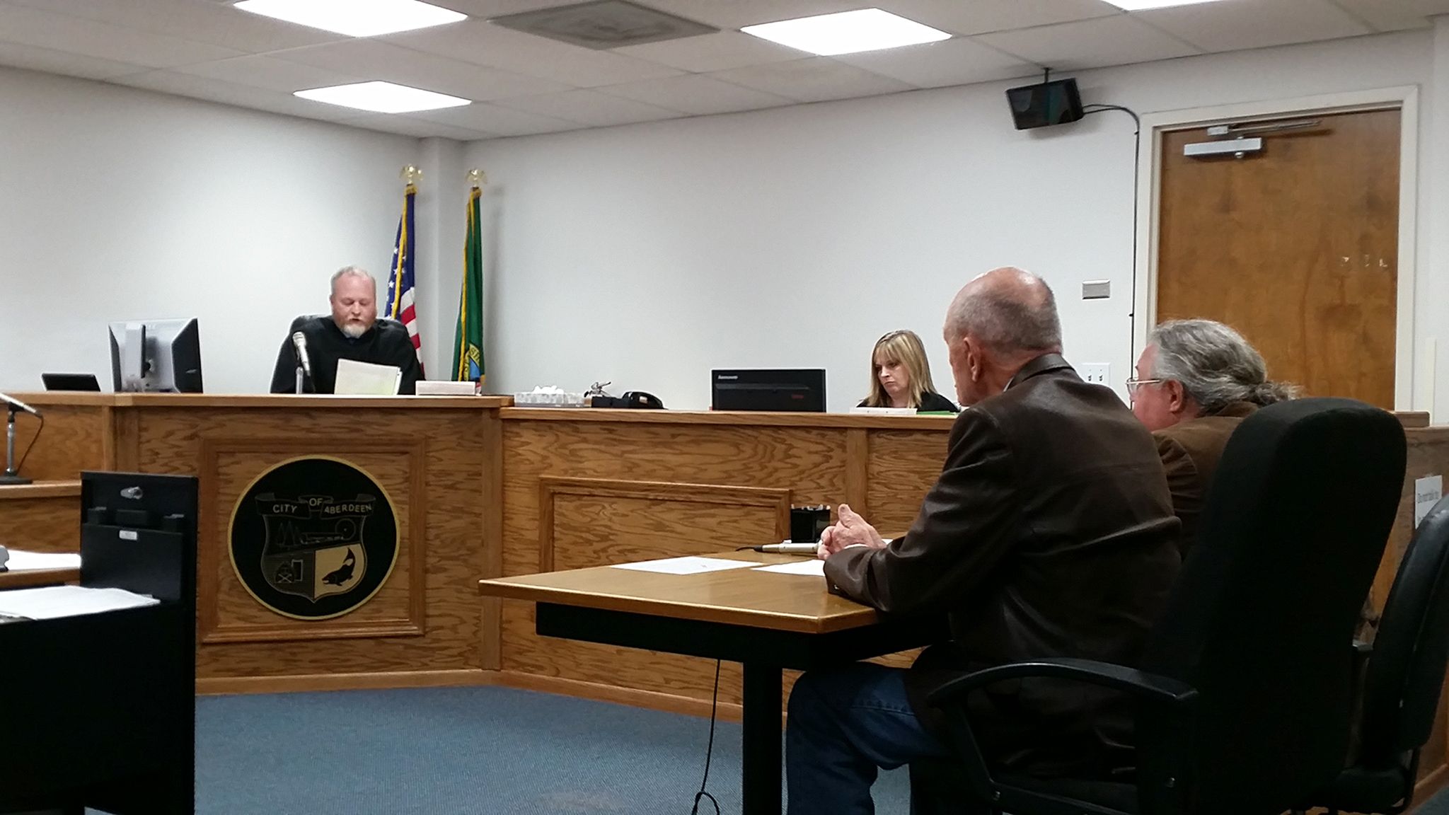 Grays Harbor County Commissioner Frank Gordon, seated in the foreground, appeared Tuesday afternoon in front of Pro-Tem Judge Chris Coker in Aberdeen Municipal Court for arraignment on the misdemeanor charge of removing or defacing political advertising. Gordon is being represented by Aberdeen attorney Jack Micheau, seated to the right of Gordon. (Terri Harber|The Daily World)