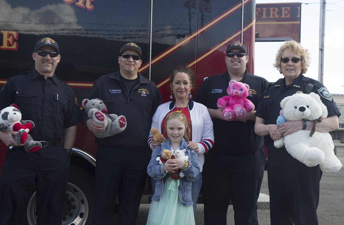 (Travis Rains | The Vidette) 7-year-old teddy bear officer Mylee Mezzell presented Grays Harbor Fire District 5 representatives and Elma Police Chief Susan Shultz with almost 80 stuffed animals April 30. From left to right: Erik Johnson, Dwight Mayberry, Joan Murphy, Jake Prater and Susan Shultz. Front: Mylee Mezzell.