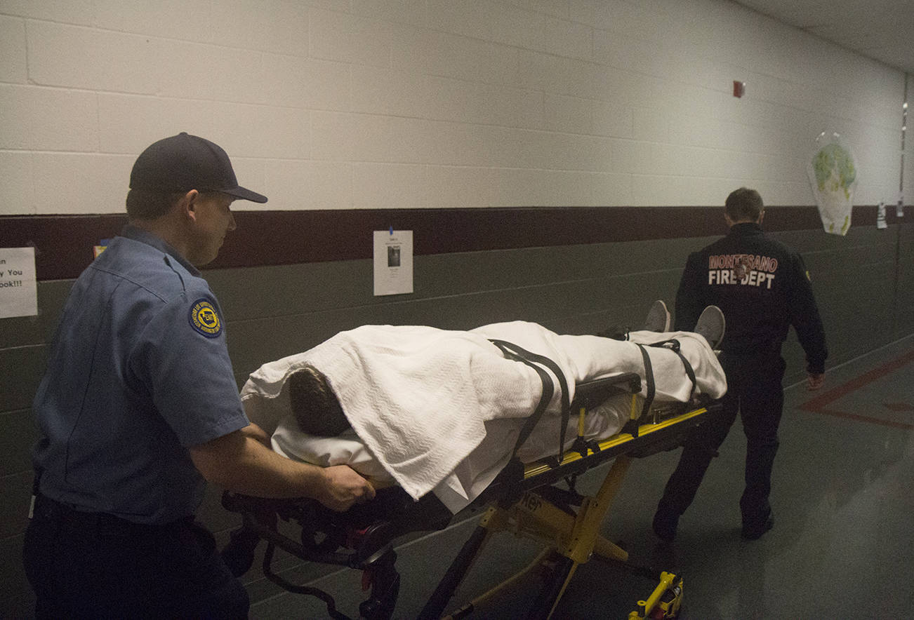 (Travis Rains | The Vidette) Jacob Sainsbury (left) and Jordan Bussard (right) wheel junior Seth Dierkop down the hallway of Montesano High School during Every 32 Minutes April 12.