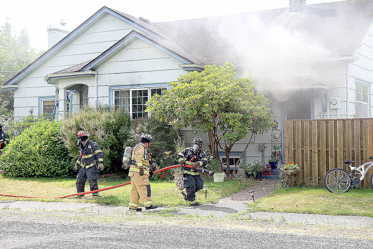 (Travis Rains | The Vidette) Fire personnel prepare to douse the garage at a house fire on the corner of North Third Street and West Spruce Avenue in Montesano July 19.