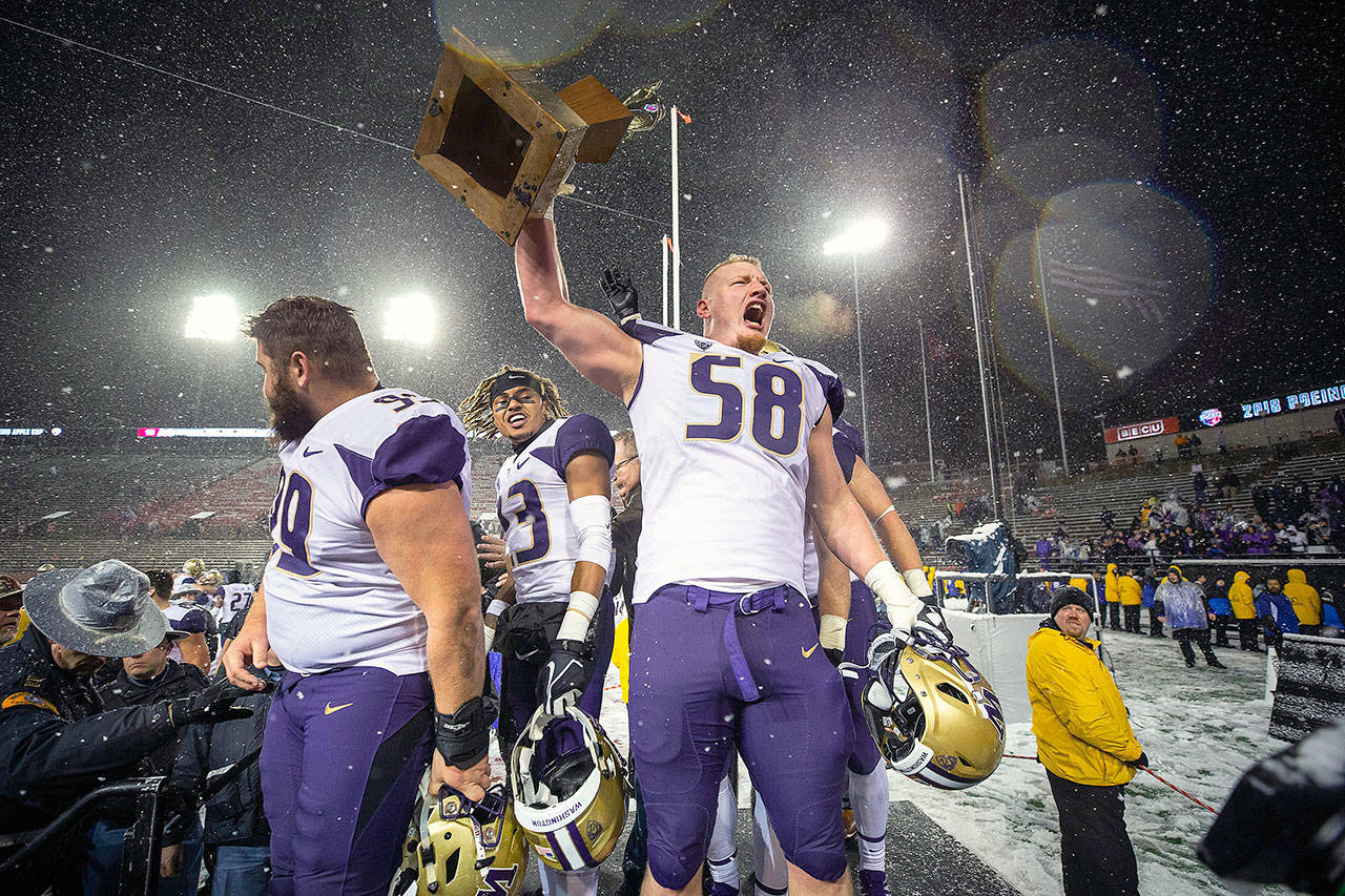 Washington’s Kaleb McGary holds the Apple Cup trophy aloft after a 28-15 win against Washington State on Nov. 23, 2018, at Martin Stadium in Pullman, Wash. Washington won, 28-15. (Dean Rutz/Seattle Times/TNS)