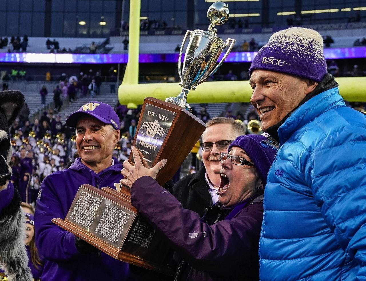 Governor Jay Inslee, right, hands off the Apple Cup Trophy to University of Washington president Ana Mari Cauce and Huskies head coach Chris Petersen, left, at Husky Stadium in Seattle on Friday. Petersen announced on Monday he will be stepping down as Huskies head coach following the Huskies’ bowl game. (Dean Rutz | Seattle Times/TNS)